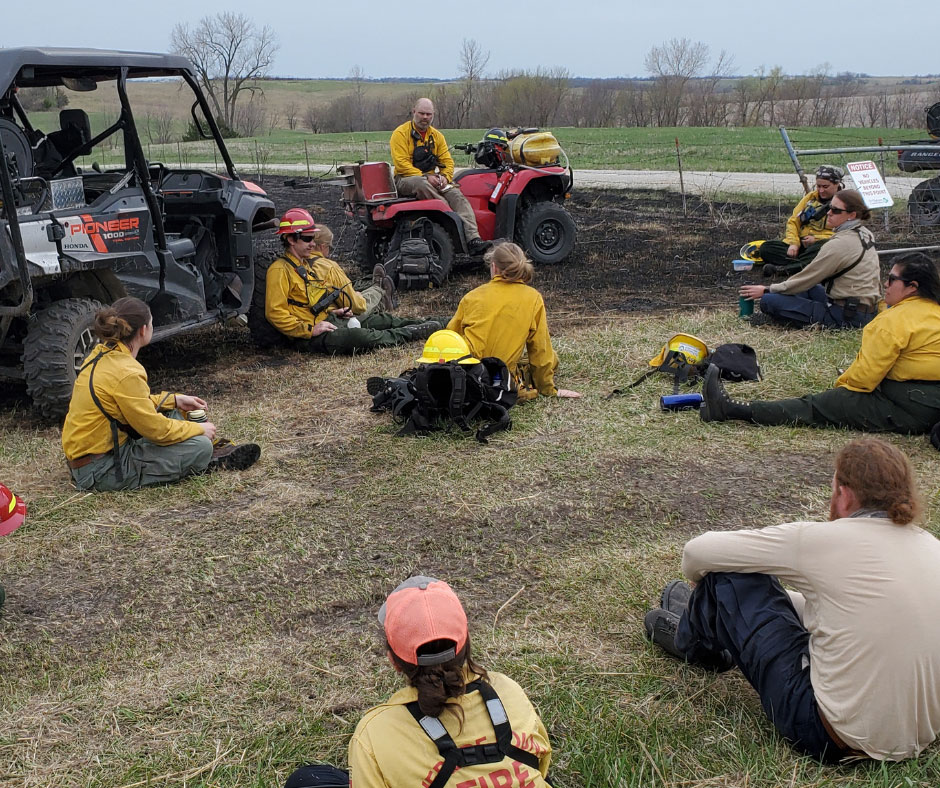 A group of fire fighters taking a break after a controlled burn of a grass field